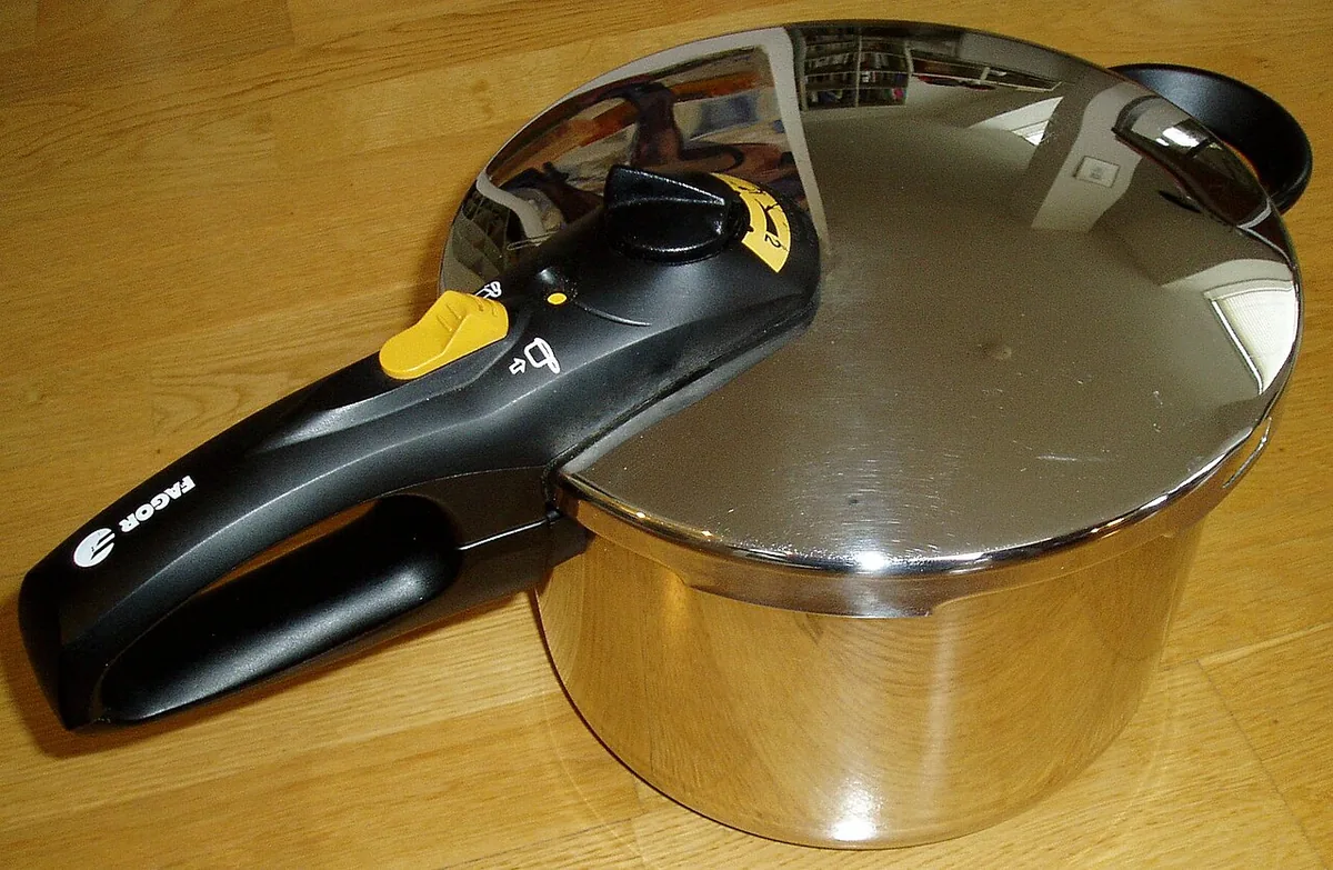 Autocuiseur métallique fermé sur une plaque de cuisson, soupape de pression au sommet du couvercle