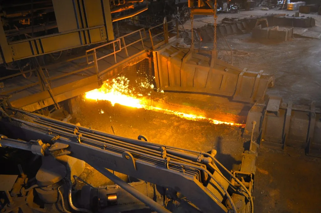 Coulée de fer en fusion orange incandescent sortant d'un haut fourneau sidérurgique