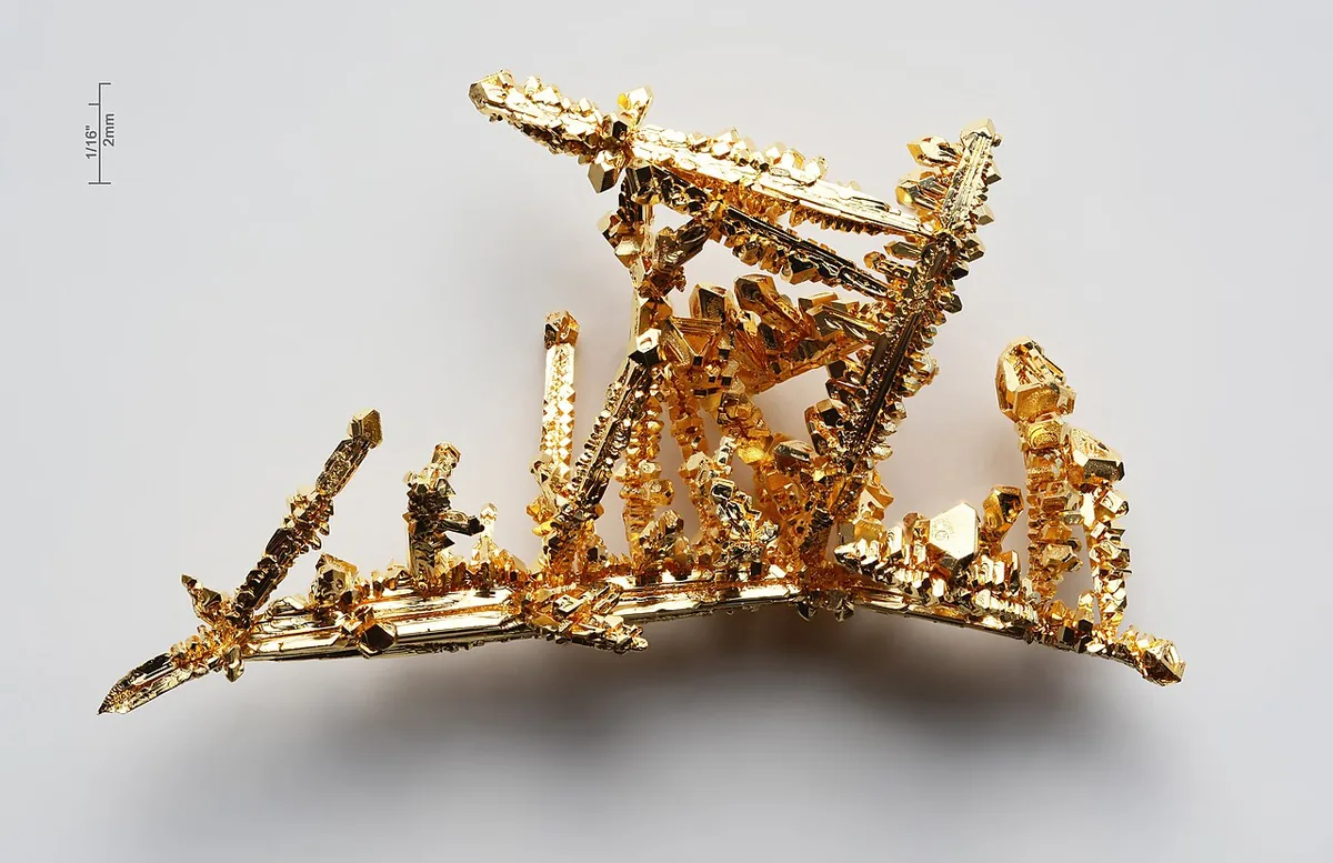 Cristaux d'or pur de synthèse aux faces géométriques brillantes, illustrant l'élément chimique Au