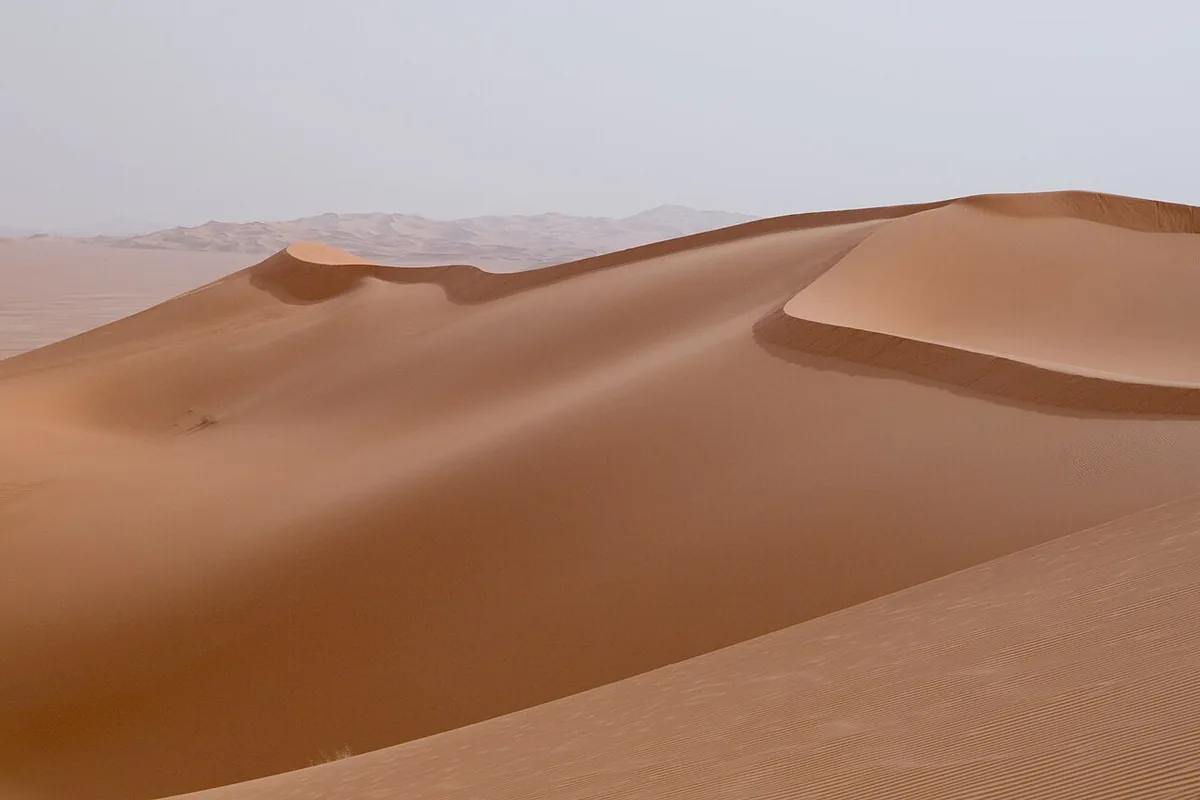 Dunes de l'erg d'Aoubari en Libye avec un lac d'oasis, sous un ciel limpide du Sahara central