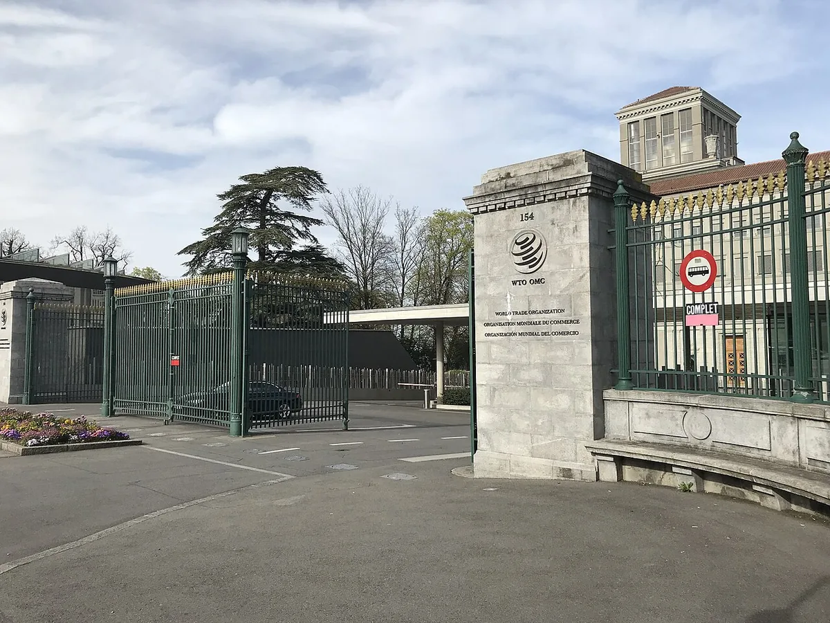 Entrée du Centre William Rappard, siège de l'OMC à Genève, avec le drapeau et l'enseigne de l'organisation