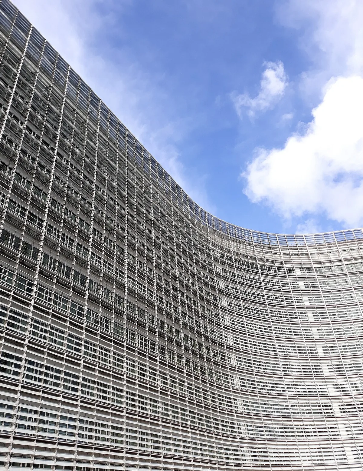Façade vitrée du bâtiment Berlaymont rénové après le désamiantage, drapeaux européens au premier plan