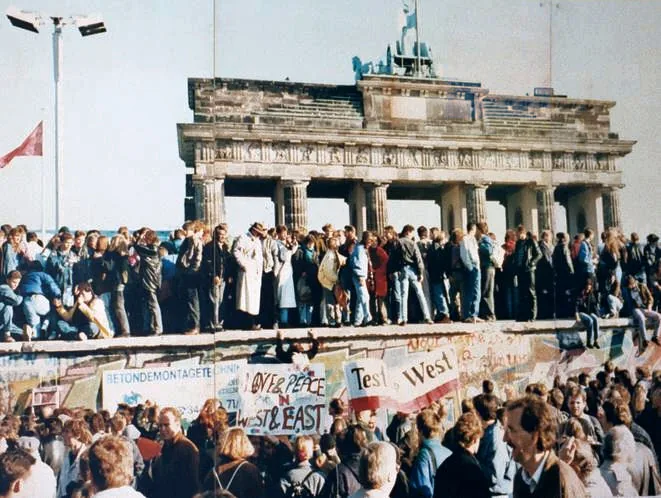 Foule d'Allemands de l'Est et de l'Ouest rassemblée sur et devant le mur à la Porte de Brandebourg en novembre 1989